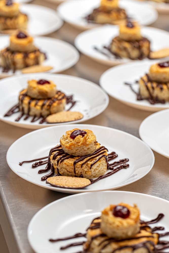 Plates of dessert featuring layered pastries drizzled with chocolate and topped with a cherry.