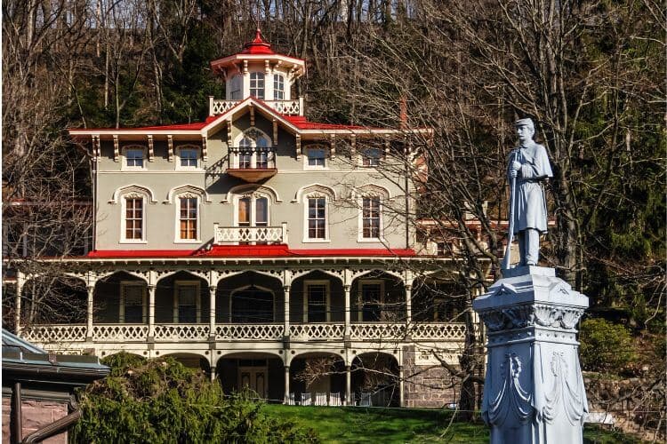 A historic building with a red-roofed turret and a statue of a soldier in the foreground.
