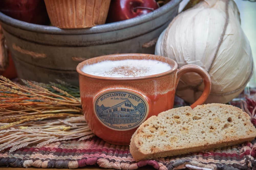 A cozy scene featuring a mug of coffee beside a slice of bread, with a backdrop of apples and decorative elements.