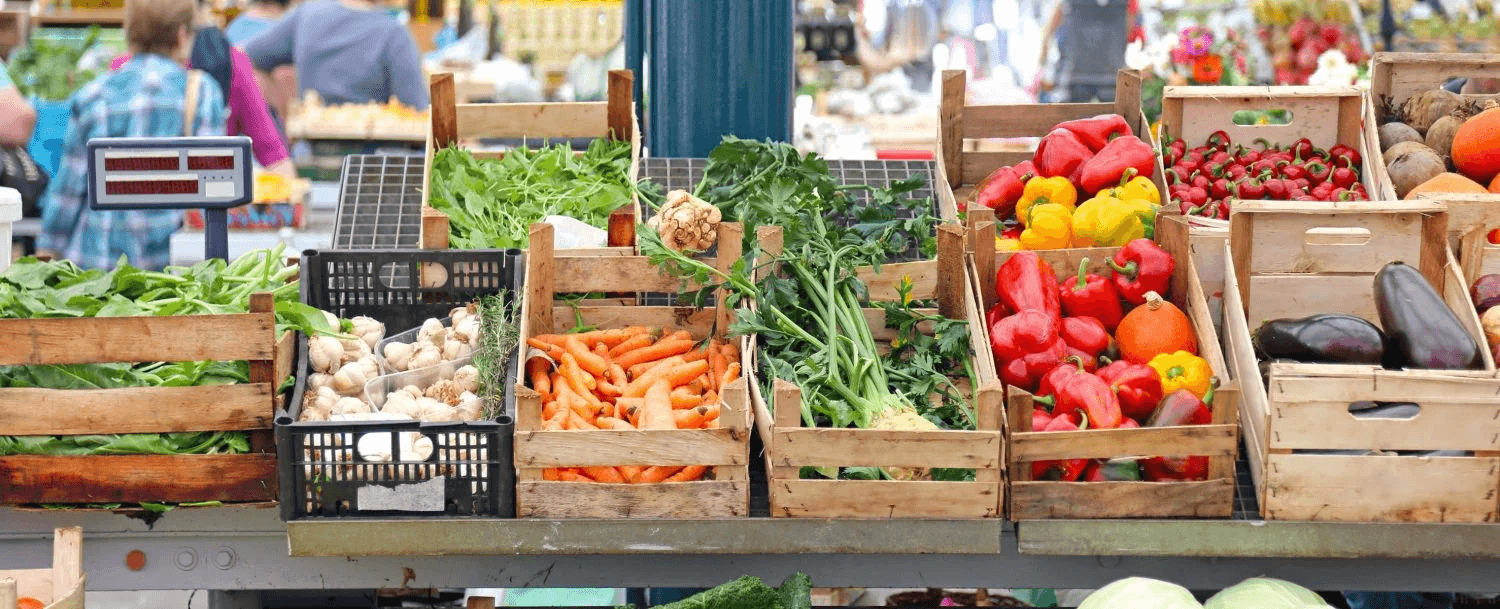 A vibrant display of fresh vegetables and fruits in wooden crates at a market.