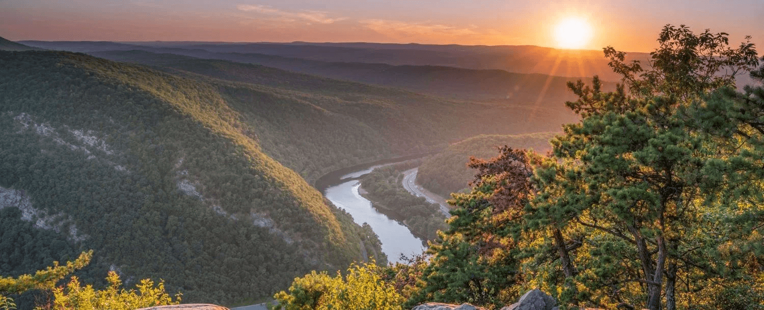 Sunset view over rolling hills and a winding river.