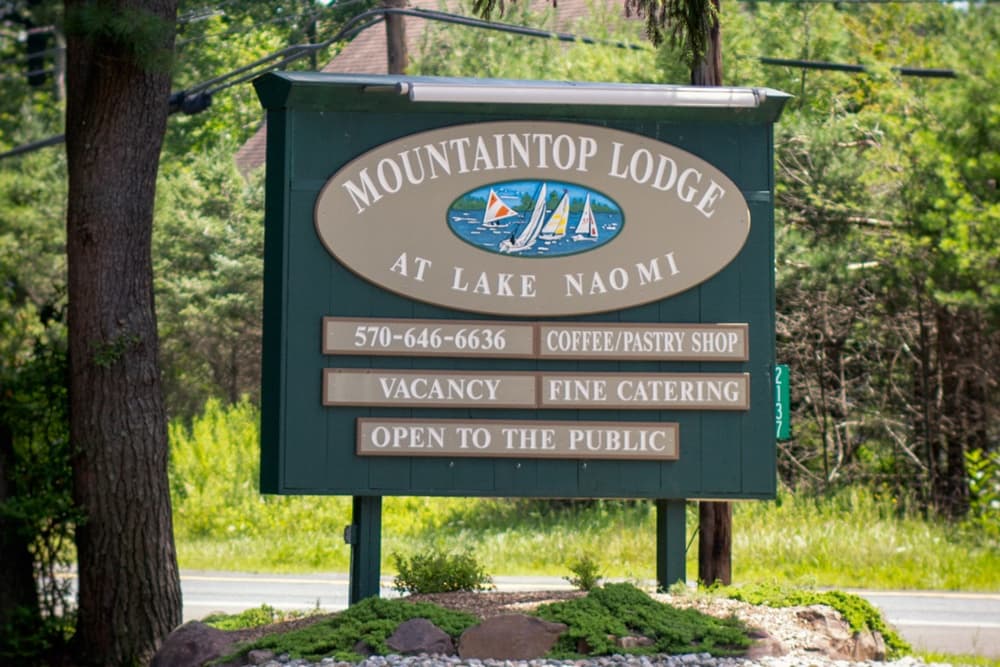 Sign for Mountaintop Lodge at Lake Naomi featuring contact information and services offered.