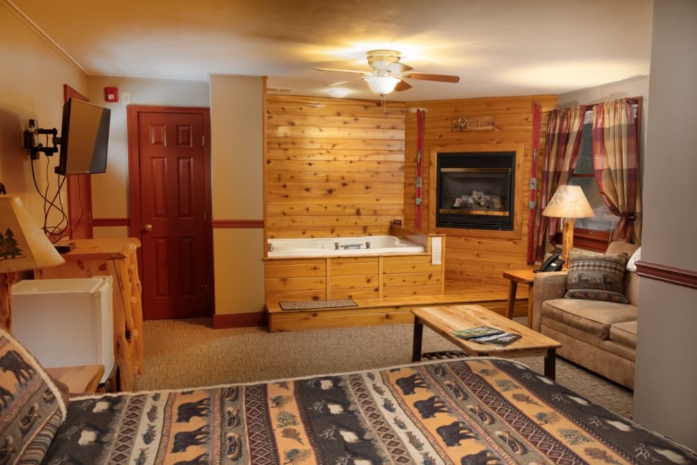 A cozy cabin interior featuring a fireplace, a spa tub, and rustic decor.