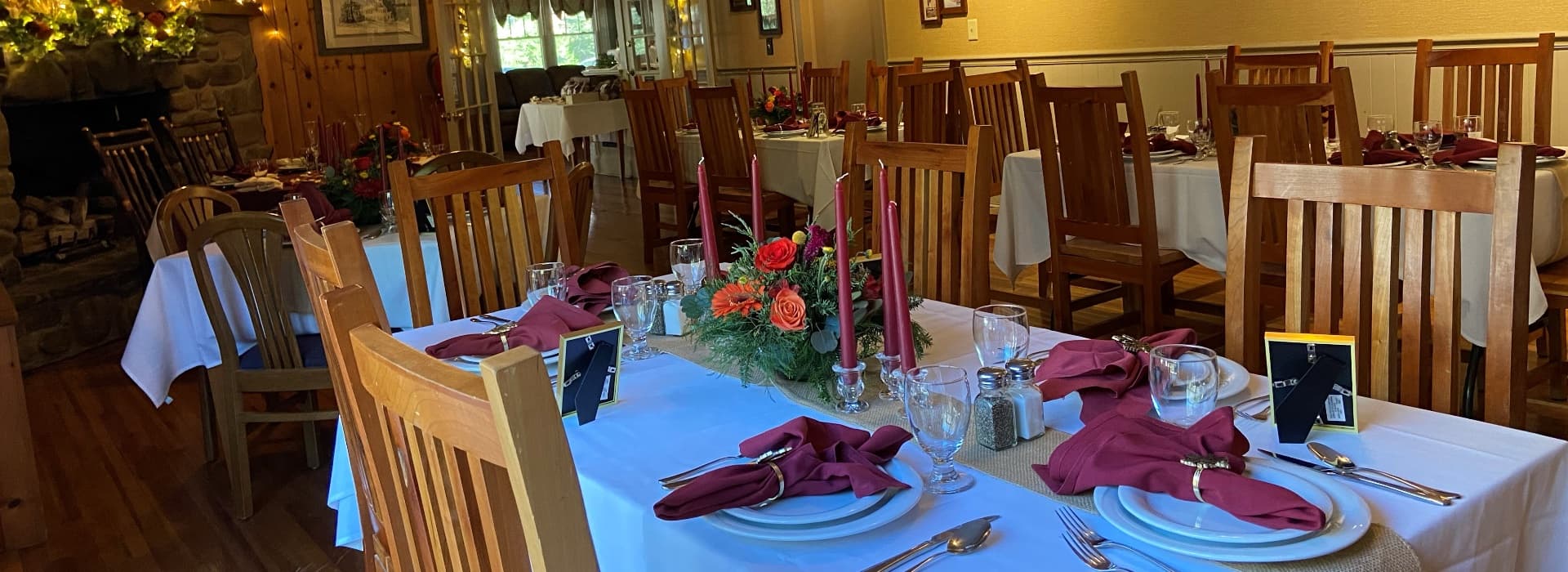 A cozy dining room set for a festive meal, featuring wooden chairs and elegantly decorated tables.