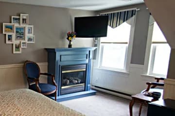 Cozy room featuring a blue fireplace, a mounted TV, a chair, and windows with natural light.