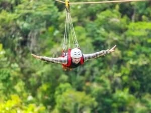 A man zip lining face down with his arms outstretched