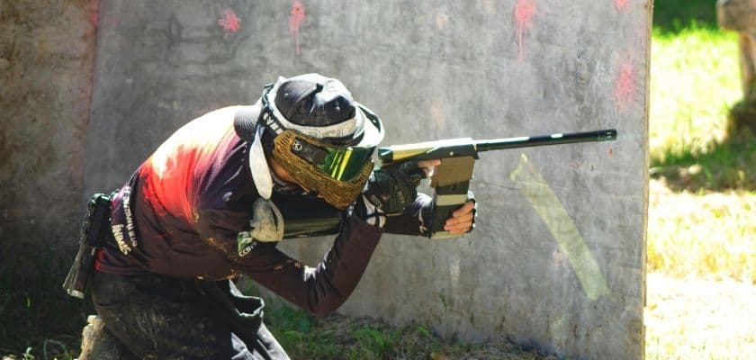 A paintball player aims from cover during a match.