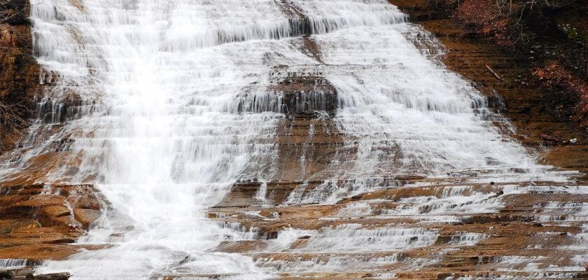 buttermilk falls cascading down over rocky ledges and into pond below
